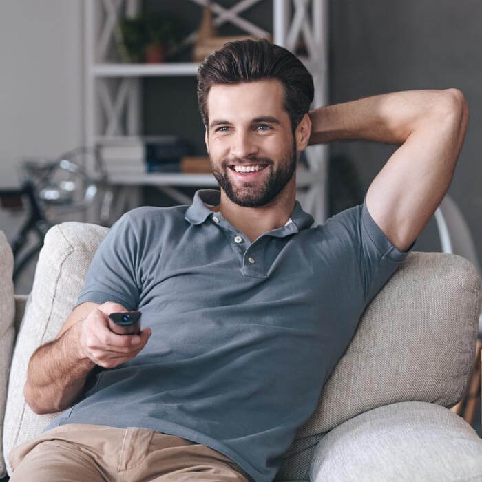 Entspanntes Fernsehen dank Bluetooth. Mann vor einem Fernseher